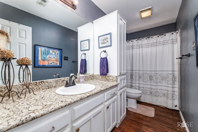 bathroom with curtained shower, toilet, wood finished floors, vanity, and visible vents