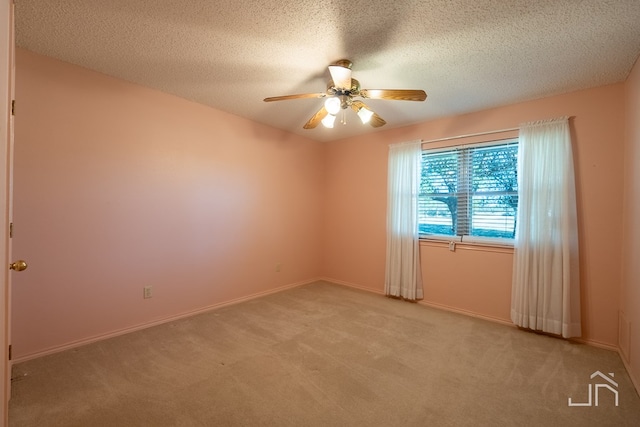 spare room with ceiling fan, light carpet, and a textured ceiling