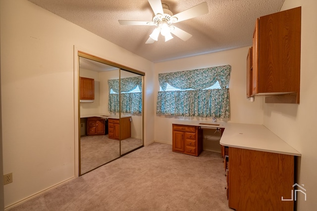 carpeted office space with a textured ceiling and ceiling fan