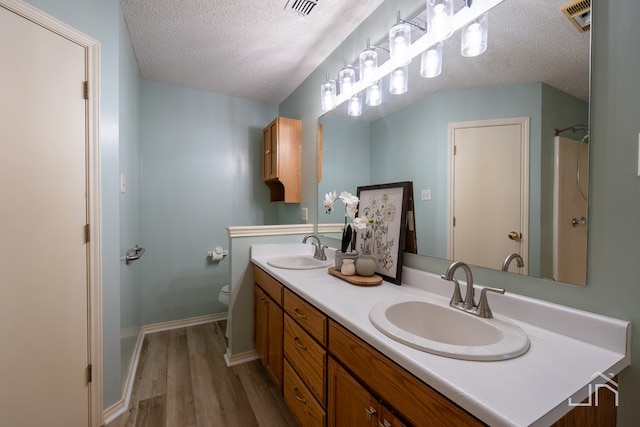 bathroom with vanity, wood-type flooring, toilet, and a textured ceiling