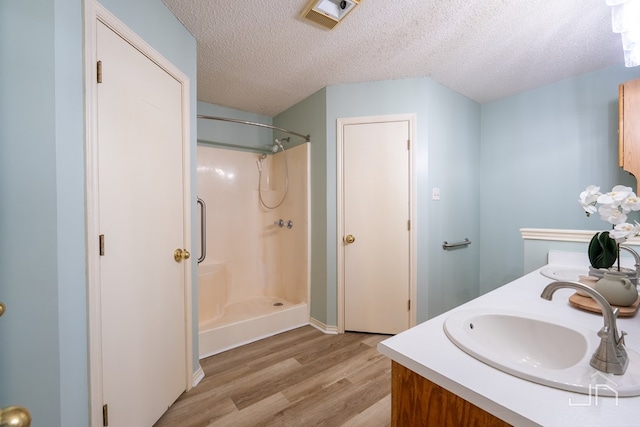 bathroom featuring vanity, wood-type flooring, a textured ceiling, and walk in shower