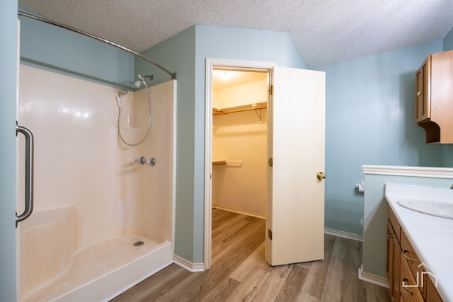 bathroom with walk in shower, wood-type flooring, a textured ceiling, and vanity