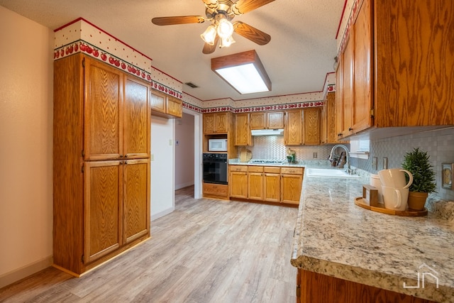 kitchen featuring tasteful backsplash, light hardwood / wood-style floors, sink, and a textured ceiling