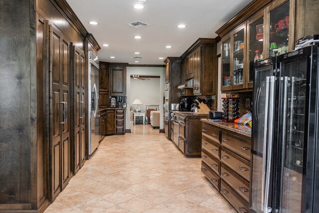 5213 Green Valley Trl, San Angelo, TX 76904 - kitchen with black fridge, dark brown cabinetry, ventilation hood, glass insert cabinets, and recessed lighting