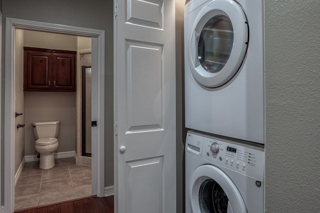 clothes washing area featuring stacked washer and clothes dryer and dark hardwood / wood-style flooring