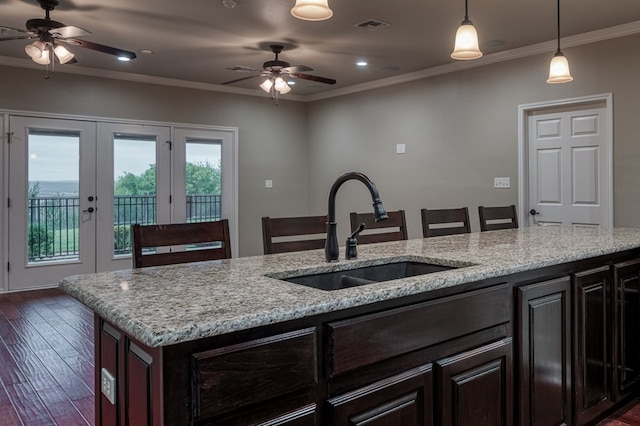 kitchen with crown molding, light stone countertops, sink, and pendant lighting