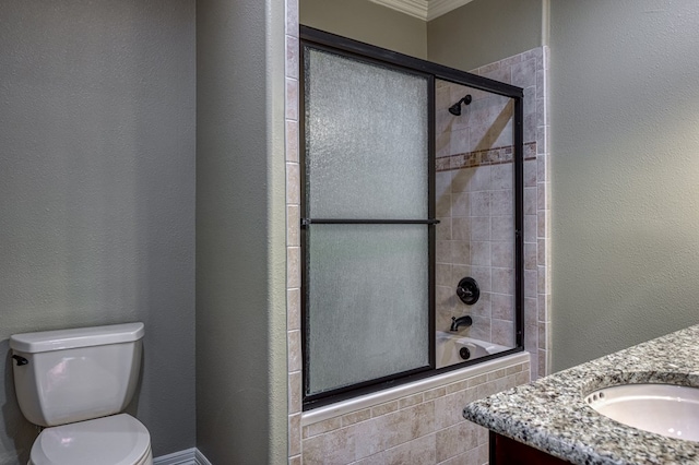 full bathroom with bath / shower combo with glass door, ornamental molding, vanity, and toilet