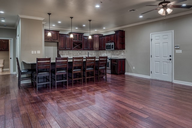 kitchen featuring pendant lighting, ornamental molding, dark hardwood / wood-style floors, and appliances with stainless steel finishes