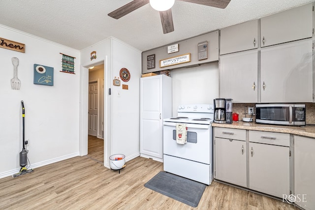2822 N St, San Angelo, TX 76901 - kitchen with white electric stove, stainless steel microwave, light wood-style floors, a textured ceiling, and a ceiling fan