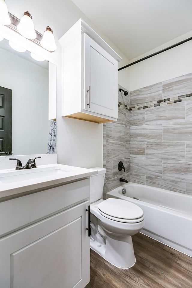 bathroom featuring washtub / shower combination, vanity, toilet, and wood finished floors