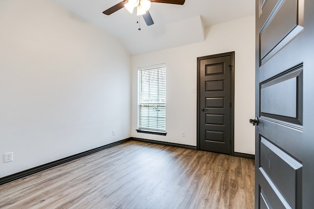 empty room with lofted ceiling, baseboards, a ceiling fan, and light wood-style floors