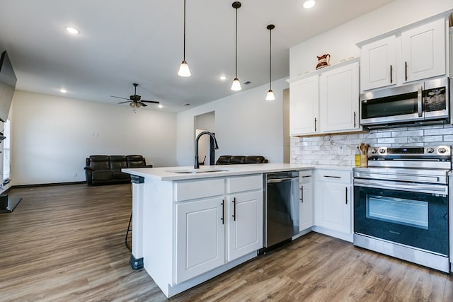 kitchen with a peninsula, appliances with stainless steel finishes, open floor plan, and a sink