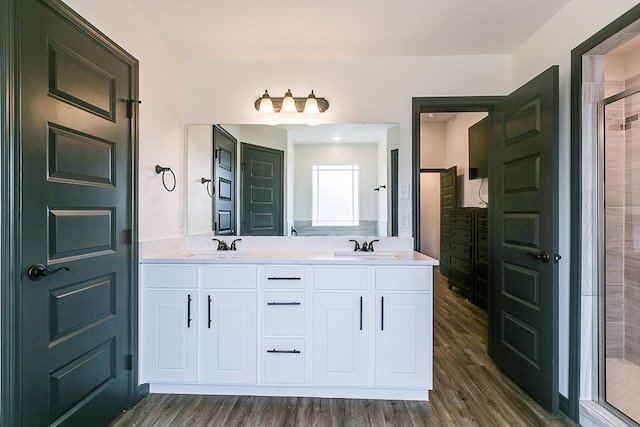 full bathroom with a sink, double vanity, a stall shower, and wood finished floors