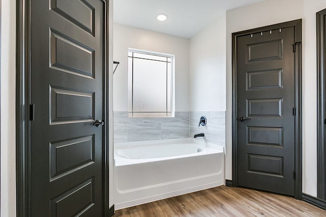 bathroom with a garden tub and wood finished floors