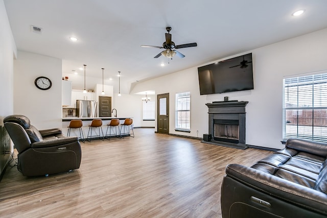 living area with plenty of natural light, visible vents, light wood-style flooring, and ceiling fan with notable chandelier