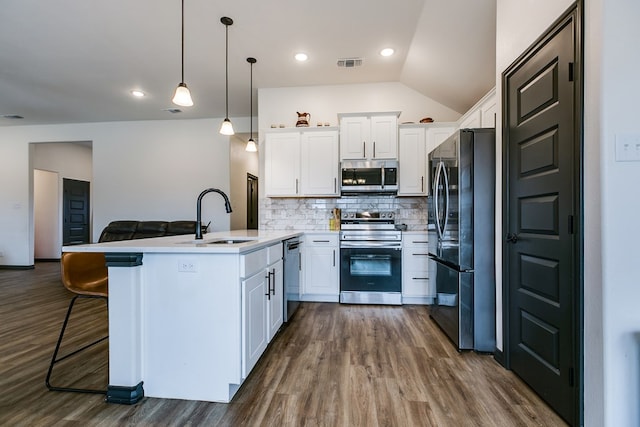 kitchen featuring visible vents, stainless steel appliances, white cabinetry, pendant lighting, and a sink