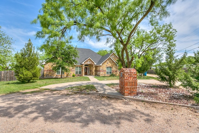 view of front of property with fence, a front yard, and stone siding
