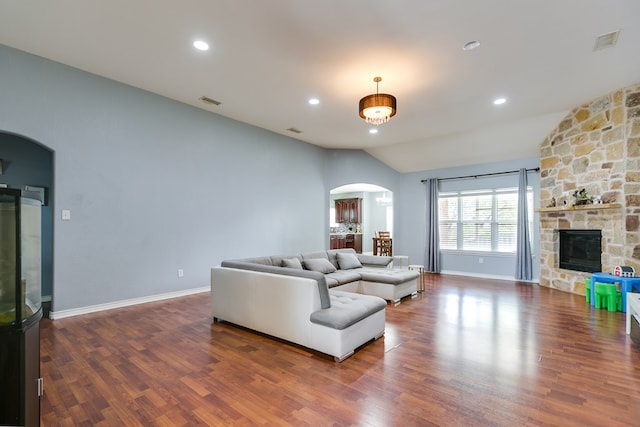 living area with arched walkways, wood finished floors, and vaulted ceiling