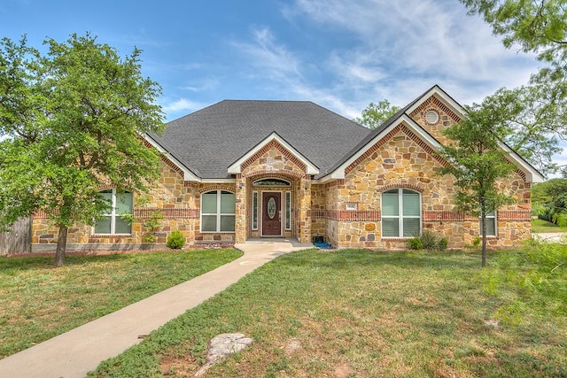 view of front of property with a shingled roof, a front lawn, and stone siding