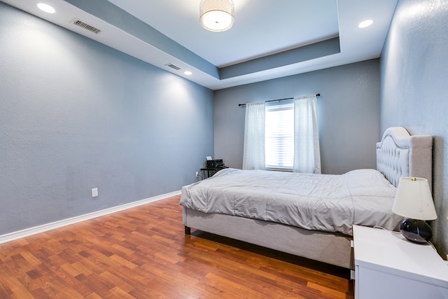 bedroom with baseboards, wood finished floors, and visible vents