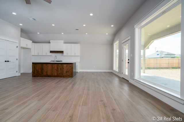 5201 Royal Oak Dr, San Angelo, TX 76904 - kitchen featuring open floor plan, lofted ceiling, white cabinetry, backsplash, and light wood-style floors