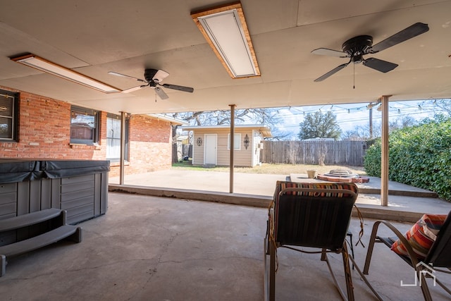 view of patio / terrace with an outdoor structure, fence, a ceiling fan, and a hot tub