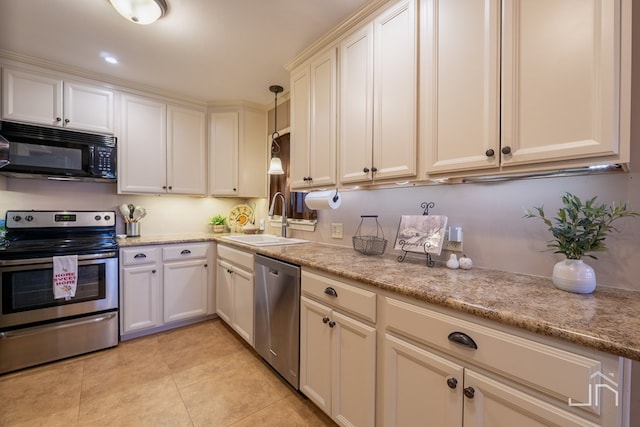 kitchen featuring light stone counters, decorative light fixtures, light tile patterned floors, stainless steel appliances, and a sink