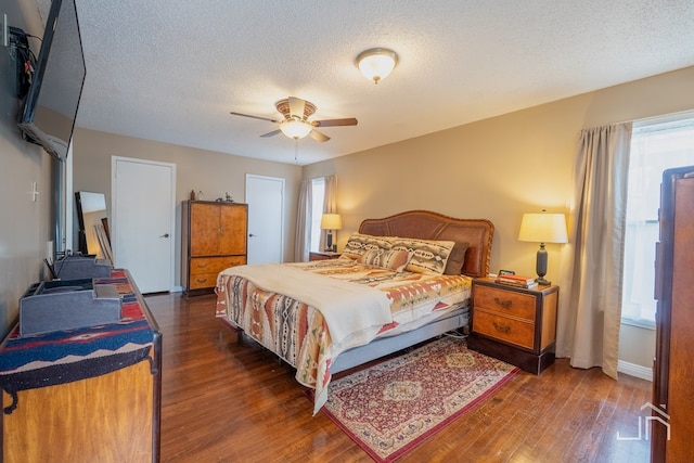 bedroom featuring ceiling fan, a textured ceiling, baseboards, and wood finished floors