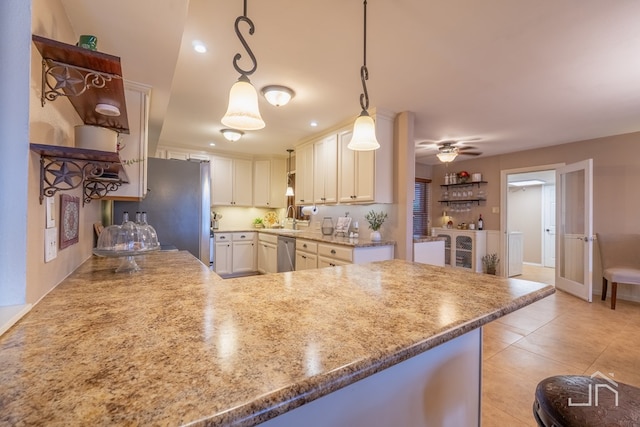 kitchen featuring light tile patterned floors, light stone counters, stainless steel appliances, a peninsula, and decorative light fixtures