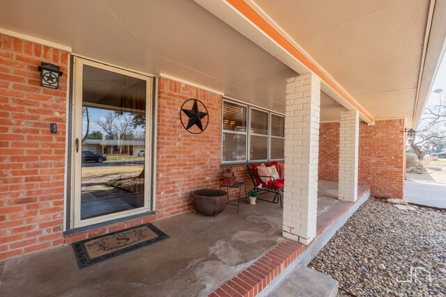 entrance to property featuring covered porch and brick siding