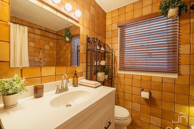 full bath with tile walls, toilet, and a textured ceiling