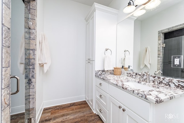 bathroom with hardwood / wood-style flooring, vanity, and a shower with shower door