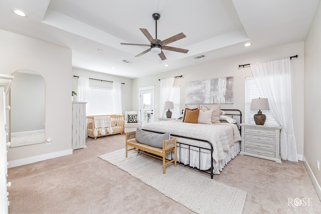 carpeted bedroom featuring a raised ceiling and ceiling fan