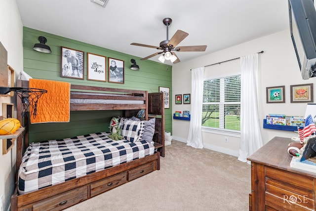 carpeted bedroom featuring ceiling fan and wood walls