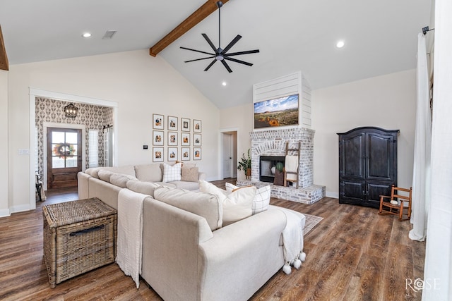 living room featuring dark wood-type flooring, ceiling fan, beam ceiling, high vaulted ceiling, and a brick fireplace