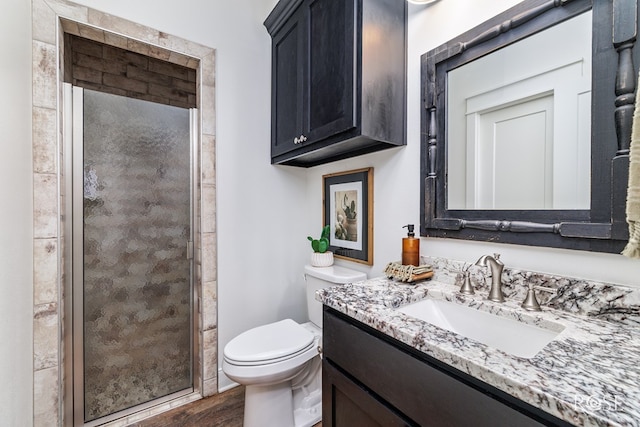 bathroom featuring wood-type flooring, toilet, an enclosed shower, and vanity