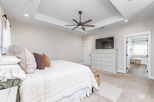 carpeted bedroom featuring a raised ceiling and ceiling fan