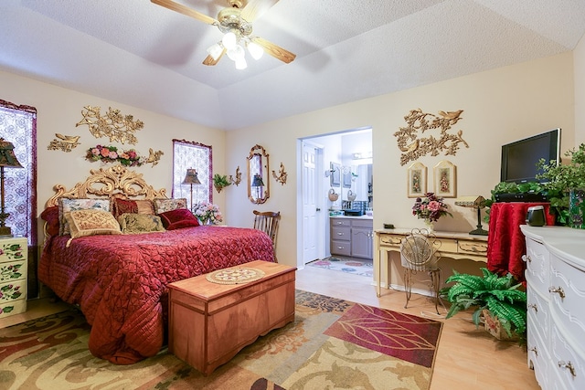 bedroom featuring connected bathroom, lofted ceiling, ceiling fan, light hardwood / wood-style floors, and a textured ceiling