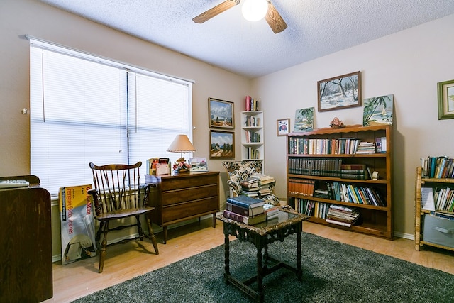 living area featuring ceiling fan, a textured ceiling, and light hardwood / wood-style floors