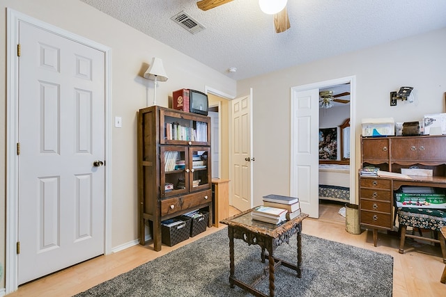 home office featuring ceiling fan, hardwood / wood-style floors, and a textured ceiling