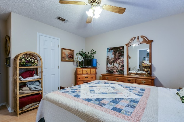 bedroom featuring ceiling fan, light hardwood / wood-style floors, and a textured ceiling