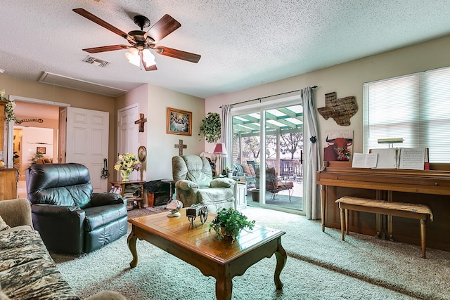 carpeted living room featuring ceiling fan and a textured ceiling