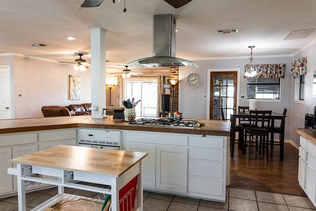 kitchen featuring white cabinetry, butcher block countertops, island range hood, and decorative light fixtures