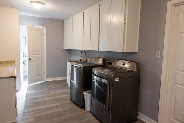 laundry room with cabinets, separate washer and dryer, sink, and light wood-type flooring