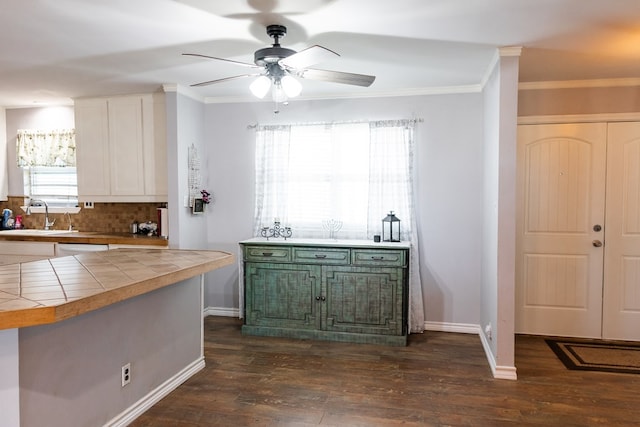 kitchen featuring sink, dark wood-type flooring, backsplash, ornamental molding, and tile countertops