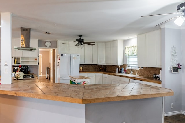 kitchen featuring white cabinetry, white refrigerator, kitchen peninsula, and island exhaust hood