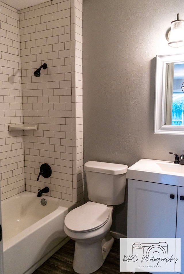 full bathroom with vanity, tiled shower / bath, wood-type flooring, and toilet