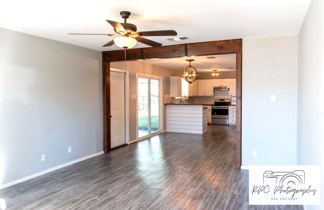 unfurnished living room featuring beamed ceiling, dark wood-type flooring, and ceiling fan with notable chandelier