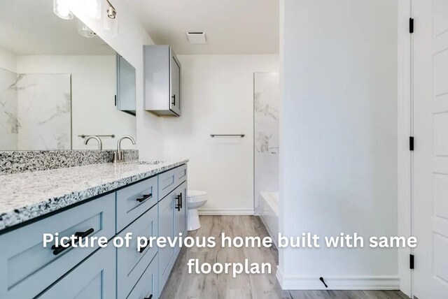 314 W 12th St, San Angelo, TX 76903 - bathroom with vanity, toilet, wood finished floors, a shower, and baseboards