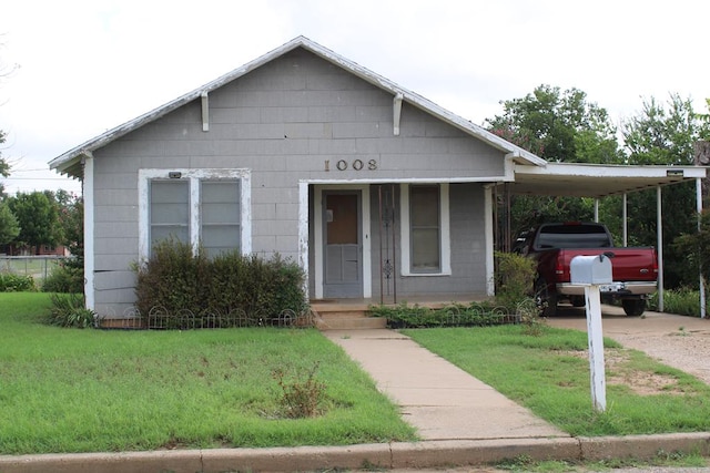 1008 10th St, Ballinger, TX 76821 - view of front facade with a front lawn, concrete driveway, and a carport